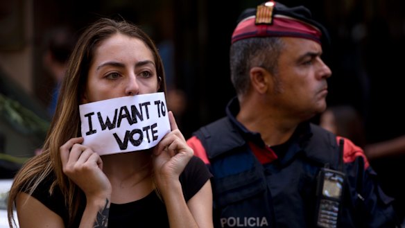 A demonstrator covers her mouth next to a Catalan police officer in Barcelona.
