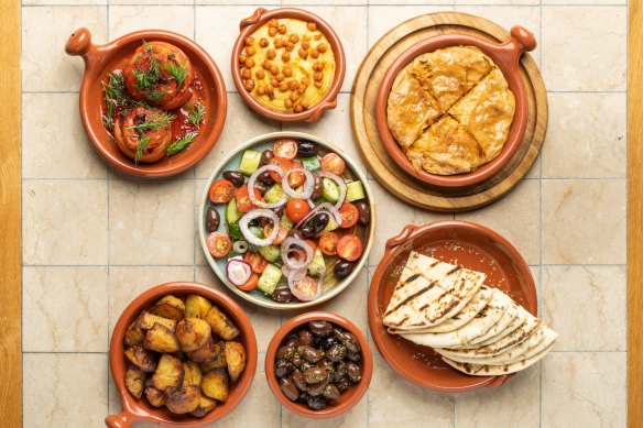 Clockwise from left: Gemista, fava dip, spanakopita, grilled pita, kalamalata olives, patates, village salad (centre). 