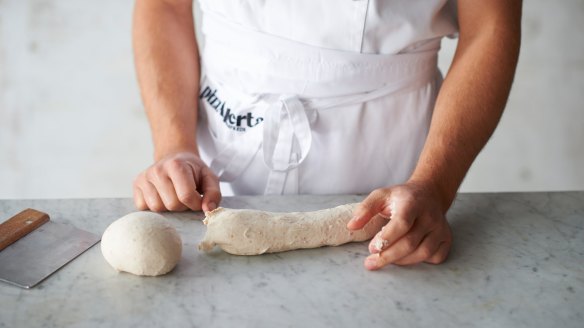 Shaping the dough step 3: Pinch the dough underneath the formed ball to separate it from the long piece of dough.