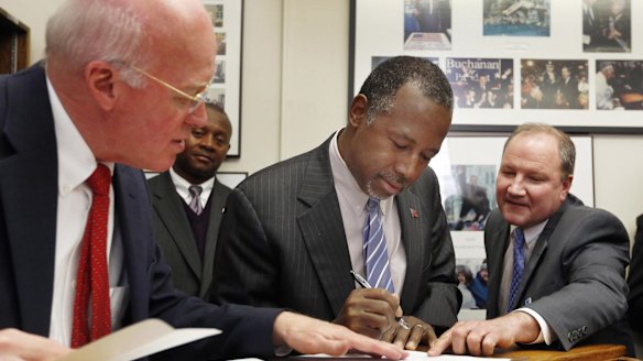 New Hampshire Secretary of State Bill Gardner (left) watches as Ben Carson gets help while filing papers to be on the nation's earliest presidential primary ballot on Friday.