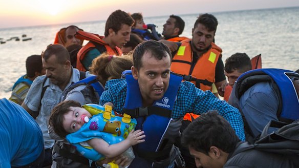 A man carries a girl as migrants arrive on a dinghy after crossing from Turkey to Kos on Thursday.