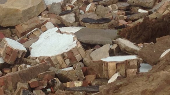 Parts of a wall lie on the rocks at the bottom of the cliff that was gouged out of the beachfront at Collaroy by the storm.