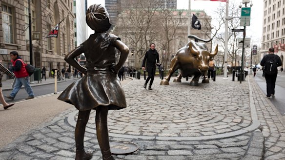 A statue titled "Fearless Girl" faces the Wall Street bull.