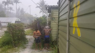 Men inside the now-closed regional processing centre at Manus Island,  showering in the rain.