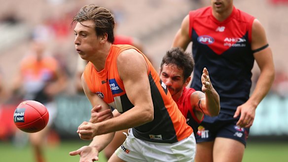 Not enough: Caleb Marchbank of the Giants handballs while being tackled by Jeff Garlett of the Demons.