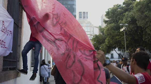 Demonstrators hang a red banner in favour of Dilma Rousseff in Rio de Janeiro on March 18.