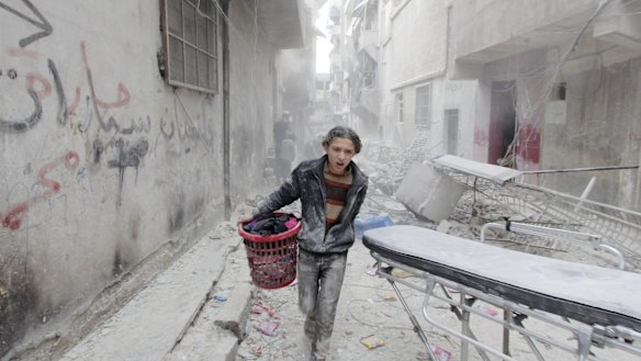 A boy carries his belongings at a site that was reportedly hit by a barrel bomb dropped by the Syrian Air Force in Aleppo's al-Fardous district in April.