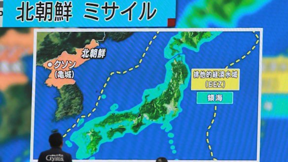 People in Tokyo walk past a public TV screen broadcasting news of North Korea's July 4 missile launch.