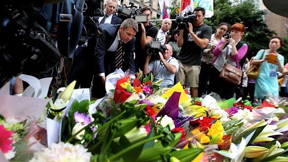 NSW Premier Mike Baird lays flowers at Martin Place after the seige where three people died early on Tuesday morning.