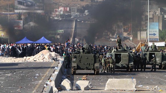 Lebanese army soldiers stand next of their armoured personnel carriers as they prepare to reopen a highway linking Beirut to southern Lebanon blocked by angry protesters, in the coastal town of Jiyeh on Monday.