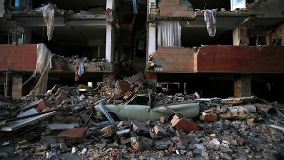 A car lays smashed by debris from the earthquake at the city of Sarpol-e-Zahab in western Iran on Monday.