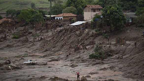 Rescue workers walk at the site where the town of Bento Rodrigues stood.