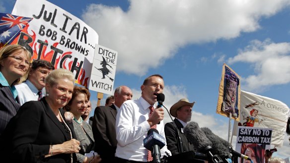 Then opposition leader Tony Abbott in front of a "ditch the witch" poster at a rally outside Parliament House in 2011.