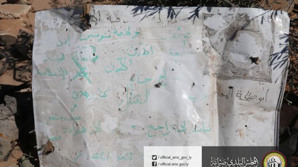 A poster with partially-erased Arabic slogans supporting the Islamic State group found at the site where US warplanes struck.