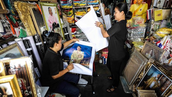 Vendors prepare portraits of Thai Crown Prince Vajiralongkorn for sale at a shop.