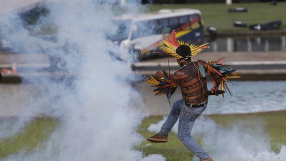 An indigenous man returns a tear gas canister to police outside the National Congress in Brasilia, Brazil, on Tuesday.
