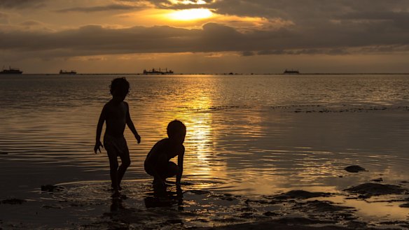 Children look for food on the beach at low tide in Dili, East Timor.