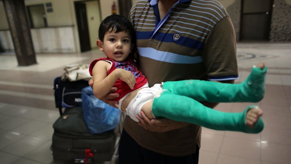 A Palestinian father carries his wounded son as they wait to be given permission to cross into Egypt at the Rafah border crossing in the southern Gaza Strip in August last year.