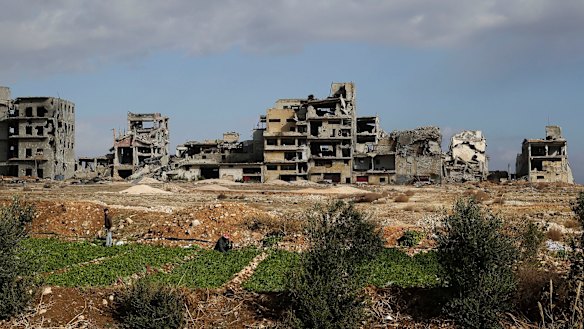 Destroyed buildings are seen as a man and his son implant vegetable in the village of al-Amrieh, south of Aleppo.
