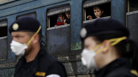 Refugees aboard a train bound for Serbia watch Czech Republic police officers maintaining order at the transit centre for refugees, near southern Macedonia's town of Gevgelija on Sunday. 
