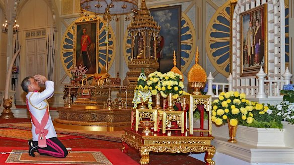 His Majesty King Maha Vajiralongkorn Bodindradebayavarangkun, or Rama X, kneels under a portrait of his late father at the Grand Palace in Bangkok, on Thursday.