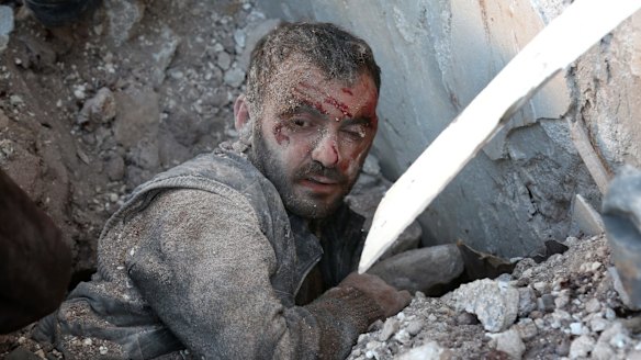 A wounded man is trapped under the wreckage of collapsed buildings after air strikes on residential areas in Yaqid al-Adas, near Aleppo.