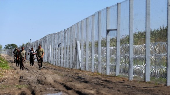 Hungarian soldiers walk along the border fence near the town of Morahalom, Hungary, on Monday.