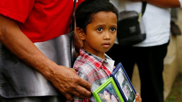 Adrian Perigrino holds portraits of his parents, both victims of extra-judicial killing, in suburban Paranaque city south of Manila in March.