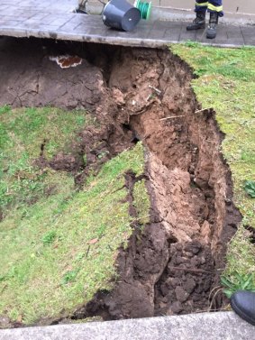 Firefighters inspect the sinkhole in Illawong.