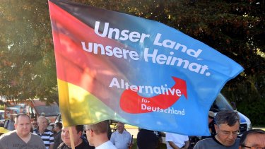 Supporters of the Alternative for Germany party hold a flag proclaiming "Our country, our homeland " 