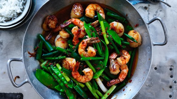 Neil Perry's spicy stir fried prawns and scallops with garlic stems, spring onions and snow peas.