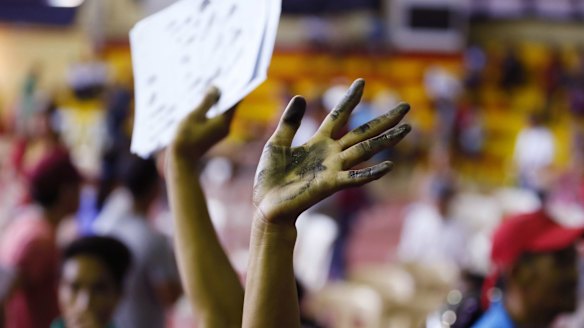 A resident waves his stained hands after being finger-printed as he undergoes processing by the authorities for allegedly being a drug-user.