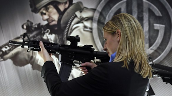 A woman tries out a SIGM400 rifle during the Defence & Security Equipment International arms fair in London in 2013.
