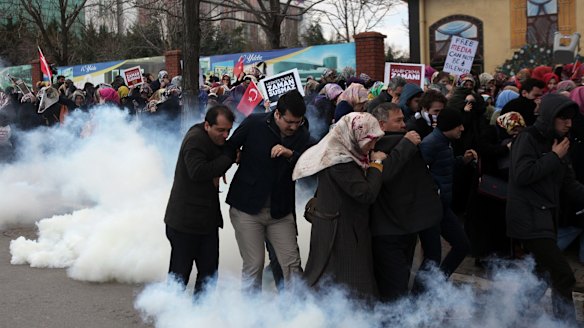 People run as riot police use tear gas and water cannons to disperse a crowd who are showing their support for the Zaman newspaper in Istanbul.