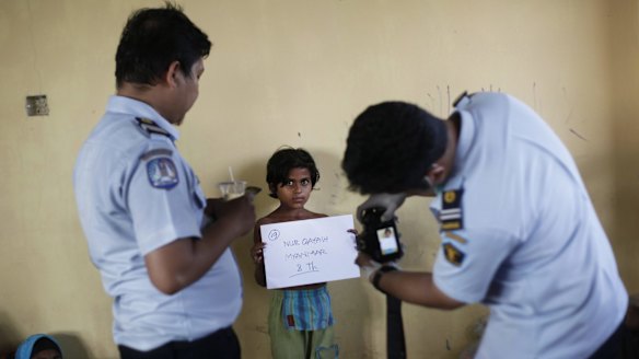 Indonesian immigration officials take photos of an ethnic Rohingya young girl at a temporary shelter for migrants in Sumatra, Indonesia, in May.