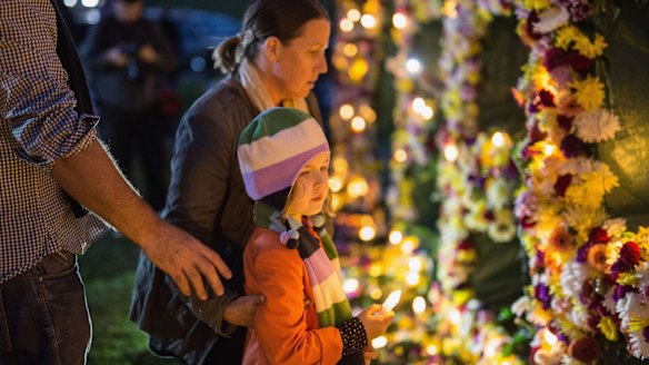 A young girl is guided to place a candle on a flower wall that reads "#keephopealive" as part of an Amnesty international vigil for the Bali nine duo, Andrew Chan and Myuran Sukumaran.