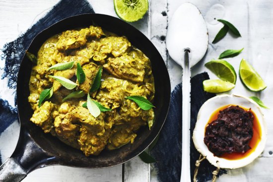 Lime wedges, fresh curry leaves and chilli sauce add colour to this chicken curry image.