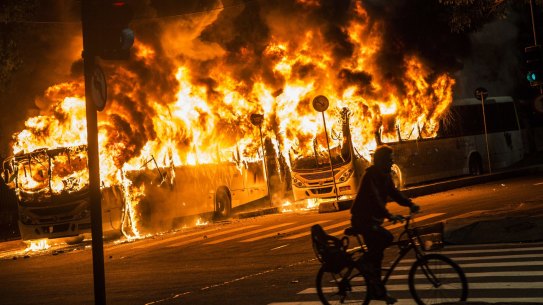 A man rides a bicycle past buses set on fire during a trade union general strike in Rio on Friday.