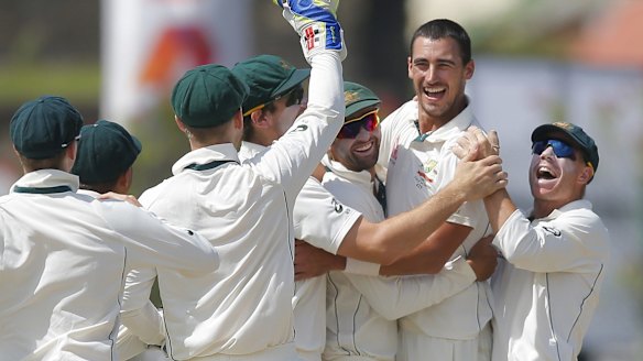 Australia's Mitchell Starc celebrates with teammates after taking a wicket with the first ball.