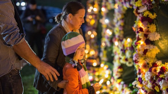 A young girl is guided to place a candle as part of an Amnesty international vigil.