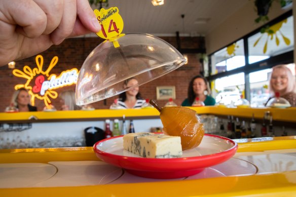 Cheeses trundle by on colour- and price-coded plates.