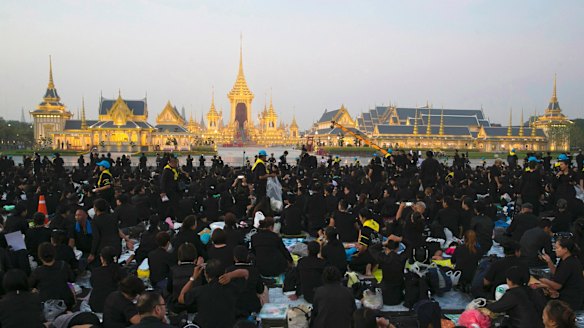 Thai mourners sits in front of the Royal Crematorium and funeral complex ahead of King Bhumibol cremation.