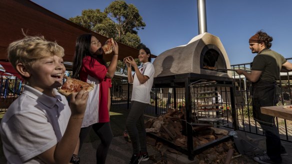 Grade 6 students Henry, Harmony and Zahraa tuck into some democracy pizza prepared by Samuel Messaoudi and Cathie Avraam at Reservoir West Primary School.