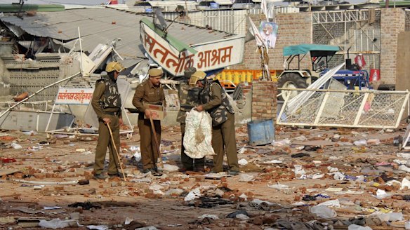 Cleaning up: Policemen collect belongings left behind after people left the ashram.