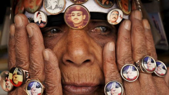 A woman supporting former dictator Ali Abdullah Saleh wears rings and badges showing Saleh and his son Ahmed Ali Saleh (in sunglasses, above her nose)  during a rally in the Yemeni capital Sanaa.