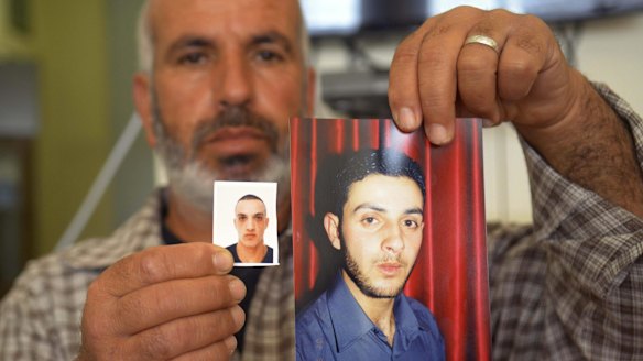 A relative with photos of the Har Nof synagogue attackers, Ghassan (right) and Uday Abu Jamal, outside the family home in Jerusalem.