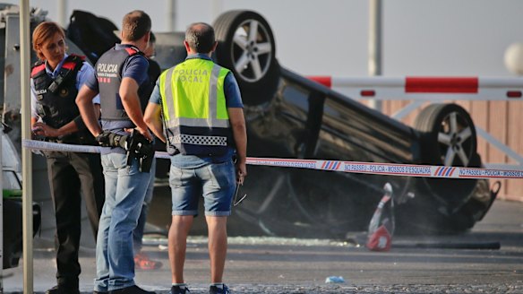 Police officers stand near an overturned car at the spot where terrorists were intercepted by police in Cambrils on Friday.