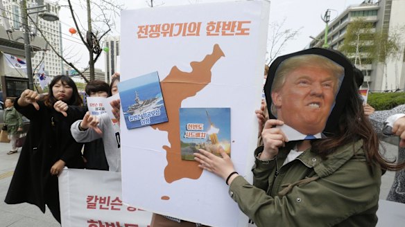 A South Korean protester holds a mask of US President Donald Trump and a Korean Peninsula map during a rally against US deployment in the region outside the US embassy in Seoul.