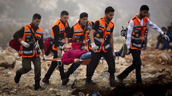 Palestinians carry an injured man during clashes with Israeli troops, after the funerals in the West Bank city of Ramallah on Monday. 