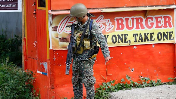 A Philippine marine signals his men to slow down as they near a corner at the frontline in Marawi city on Sunday.